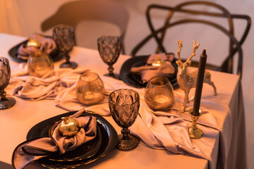 Close up of festive Christmas table setting with empty wine glasses and black plate