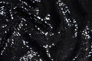 Silver sequins pattern. Sequins on black wool  or jersey fabric as background.