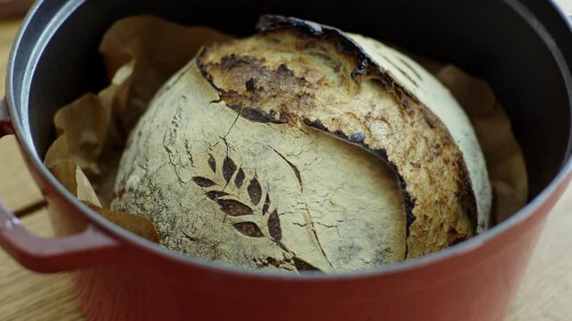 Close up slow motion uncovering removing cover on an cast iron tray with  sourdough bread loaf inside