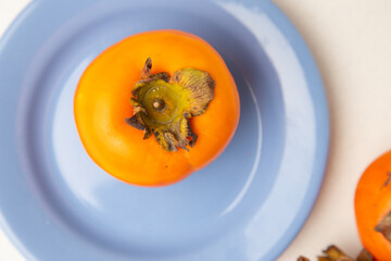 Persimmon fruit on white background and blue plate
