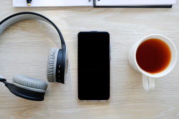 Headphones, telephone and tea on the table.