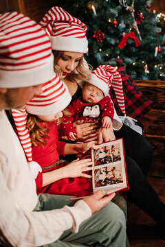 The family looks at the photos in the album near the Christmas tree