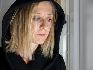 BLOND SPANISH WOMAN DRESSED IN BLACK, WITH HOOD IN THE ROOM OF HER HOUSE, SHOWING SADNESS, ANGER,...