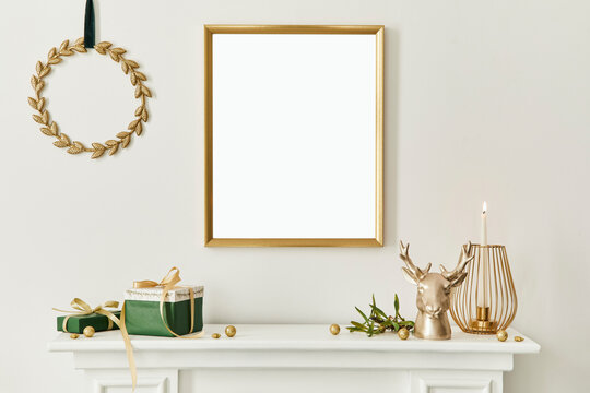 Christmas composition with gold mock up poster frame, white chimney and decoration. Christmas trees and wreath, candles, stars, light and elegant accessories. Template.