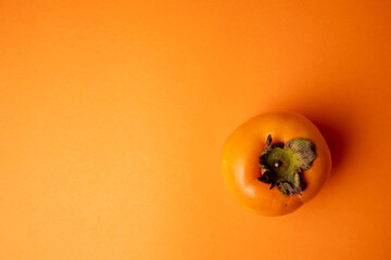 Persimmon fruit on orange background