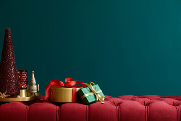 Christmas composition on the red velvet bench with decoration, gifts, wreath, lantern and accessories. Copy space. Red and green color. Template.