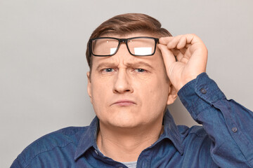 Portrait of serious man with glasses, peering at something interesting