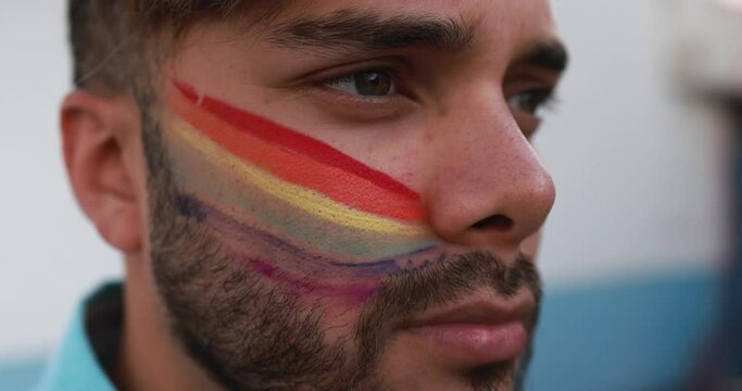 Young gay man with rainbow flag painted in his face - Lgbt concept