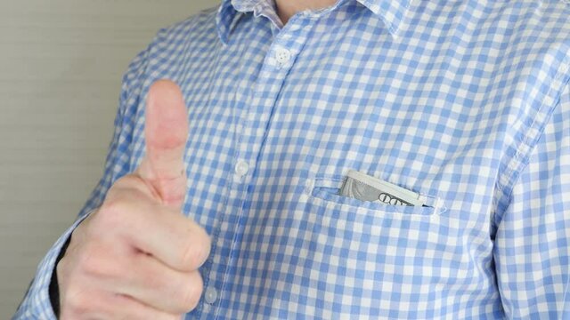 A woman's hand puts money in a man's pocket close-up. The man gives a thumbs-up sign of approval. The transaction, the bribe.
