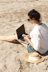 Young woman using laptop computer on a beach. Vacation lifestyle communication. Holds a Bank card in his hands. The concept of online shopping or online shopping