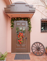 Fototapeta na wymiar stylish family house entrance brown door on pink wall, Christmas decorated