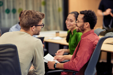 Group of young happy multi racial coworkers communicating and sharing ideas while working together...