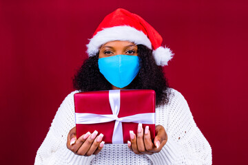 latino joyful pretty woman in medical mask and red santa claus hat laughing isolated on red background she is happy and excited full of fun