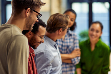 Group of happy diverse multi ethnic business people standing together in modern office and discussing project results for sharing ideas