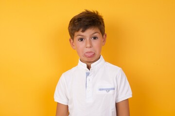 Body language. Disgusted stressed out Cute Caucasian little boy standing against yellow background , frowning face, demonstrating aversion to something.