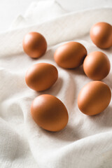 A photo of raw brown eggs on the white kitchen towel