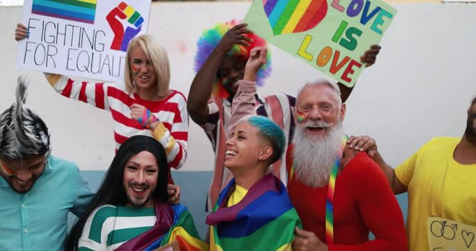Gay people dance with banners and rainbow flags at pride party outdoor - Lgbt concept