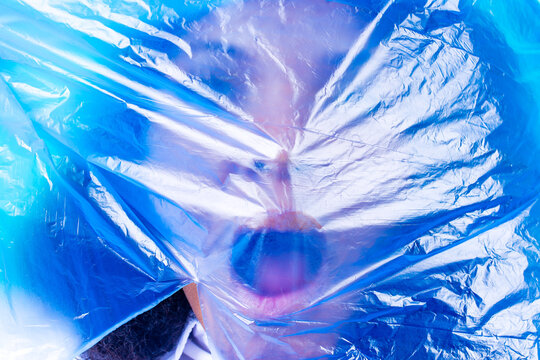 unhappy female with plastic bag on her head against blue wall studio