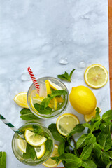 Refreshing drinks for summer, cold sweet and sour lemonade juice in the glasses with sliced fresh lemons. Refreshing summer drink. Traditional lemonade with lemon, mint and ice. Selective focus