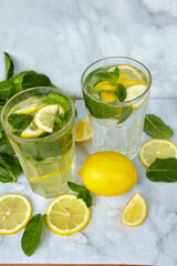 Refreshing drinks for summer, cold sweet and sour lemonade juice in the glasses with sliced fresh lemons. Refreshing summer drink. Traditional lemonade with lemon, mint and ice. Selective focus