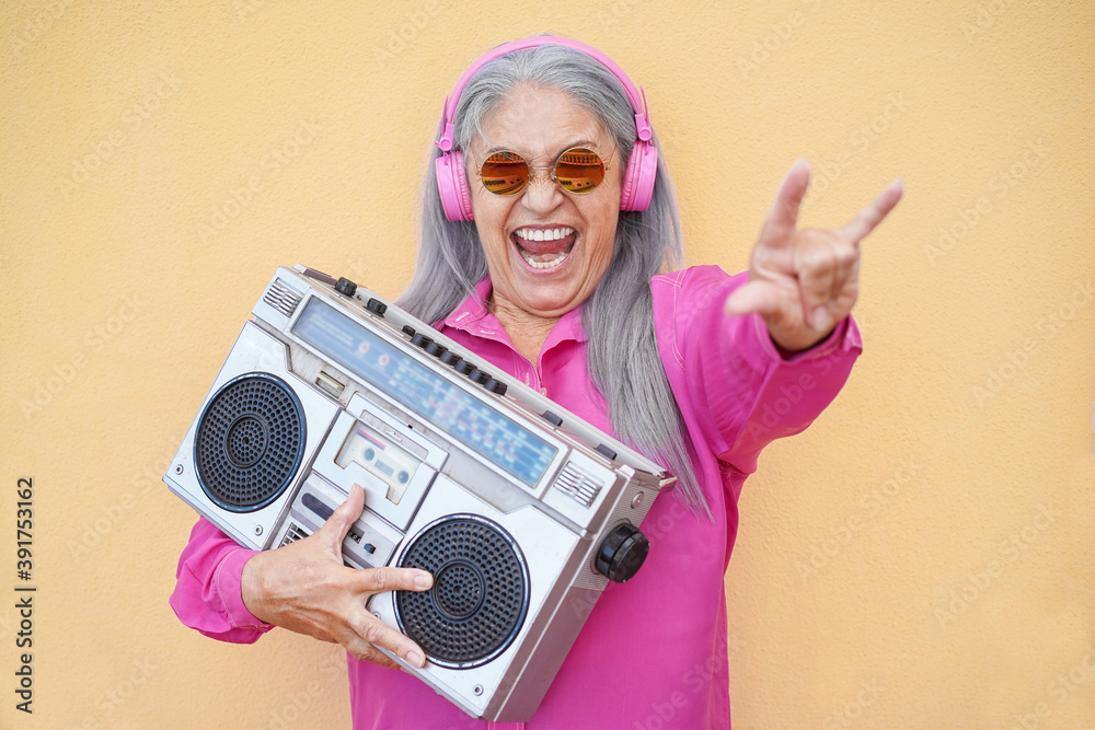 Wall mural happy senior woman dancing and holding vintage stereo - focus on face