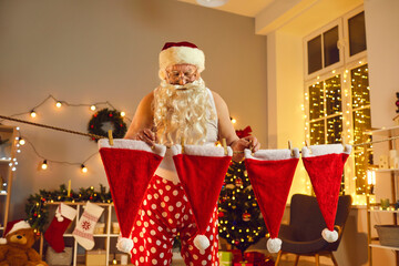 Old Santa Claus hanging his red caps to dry after doing laundry on winter holidays