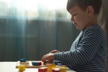 Educational toys, Cognitive skills, Montessori activity. Montessori kid learning about color, shape, sorting, arranging by engaged colorful wooden sensorial blocks.