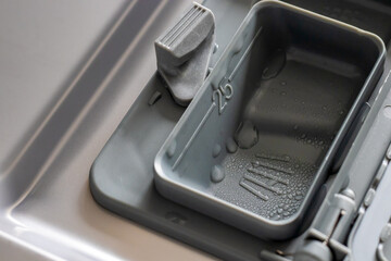 close up opened dishwasher detergent dispenser with water drops
