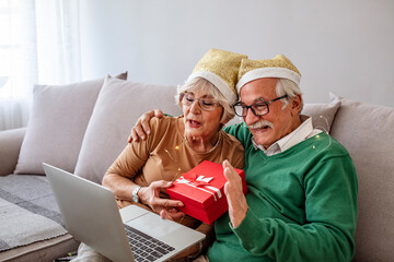 Shot of senior couple talking to his friends/family in video call from home. Senior couple usinglaptop for an online meeting in video call. Friends/family having online conversation during Christmas