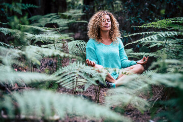 Relaxed beautiful lady do meditation sitting in the middle of nature plant outdoor - people in...