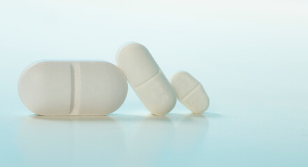 Three white  tablets of different sizes, dosage