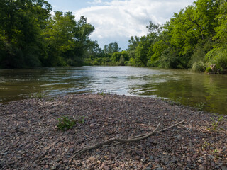 Summer landscape of the river from a pebble island and forested shores during a sunny day.