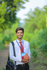 Young indian banker holding clay piggy bank in hand
