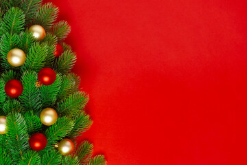 postcard from the branches of a Christmas tree with red and gold balloons on a rich background, copy space.