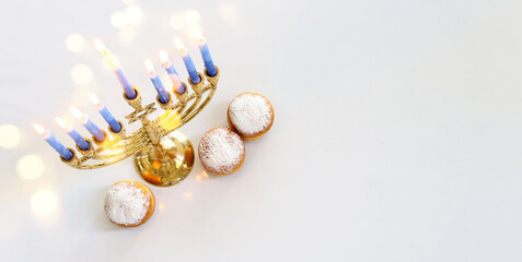 Image of jewish holiday Hanukkah with menorah (traditional Candelabra), donut and wooden dreidel (spinning top)