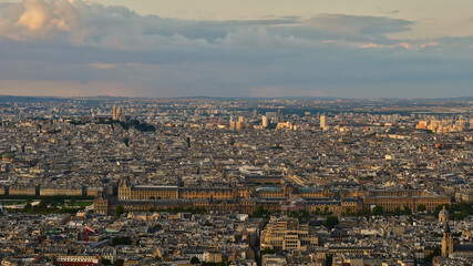Fototapeta premium Stunning panorama view over the northern historic city center of Paris, France with Louvre Museum complex and Sacre-Coeur cathedral located on Montmarter hill in the beautiful evening light in fall.