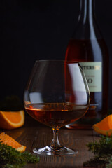 A glass of cognac and the bottle. A Christmas photo with lights and orange