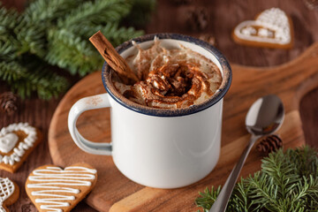 a cup of warm cacao with whipped cream and sprinkles of chocolate with Christmas decorations and gingerbread man