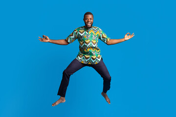 Fototapeta na wymiar Carefree black man in african costume posing in the air