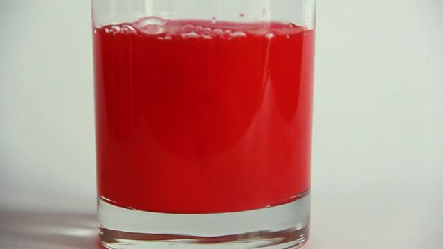 Paint in a glass. Red paint in clear water