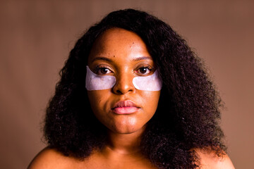 beautiful hispanic woman with collagen patches undereye patch wrinkles in brown background unretouched photo