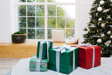 Elegant christmas gifts on bed near christmas tree and window.
