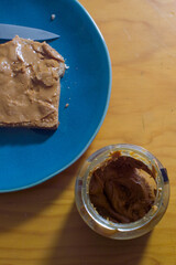Peanut butter on toast on green plate on wooden table and hot espresso coffee