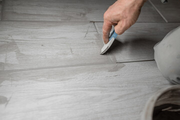 Grouting ceramic tiles. Tilers filling the space between tiles using a rubber trowel.