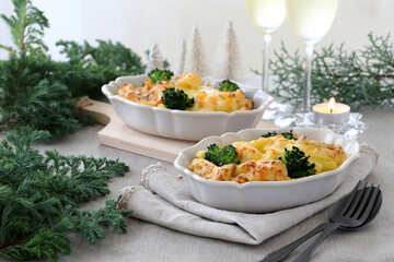 Homemade gratin with shrimp and cheese in baking dishes on Christmas decoration table.　マカロニグラタン