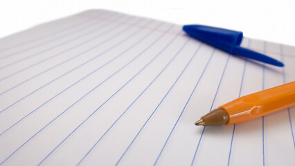 Close-up yellow pen on a ruler notebook. Against the background of a blue cap.