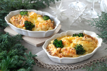 Homemade gratin with shrimp and cheese in baking dishes on Christmas decoration table.　マカロニグラタン