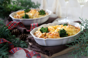 Homemade gratin with shrimp and cheese in baking dishes on Christmas decoration table.　マカロニグラタン