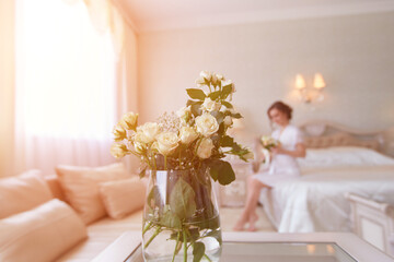 A girl with a bouquet of flowers in a negligee is sitting on the bed in a beautiful boudoir