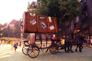 Huge suitcase of the tourist with labels of the different countries on a roof of carriage with two horses